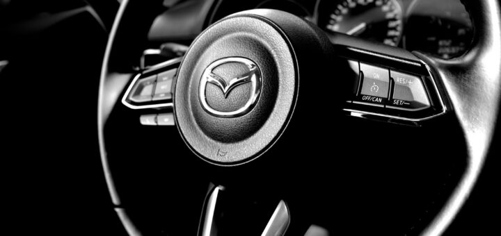 Black-and-white close-up of a Mazda steering wheel and dashboard gauges